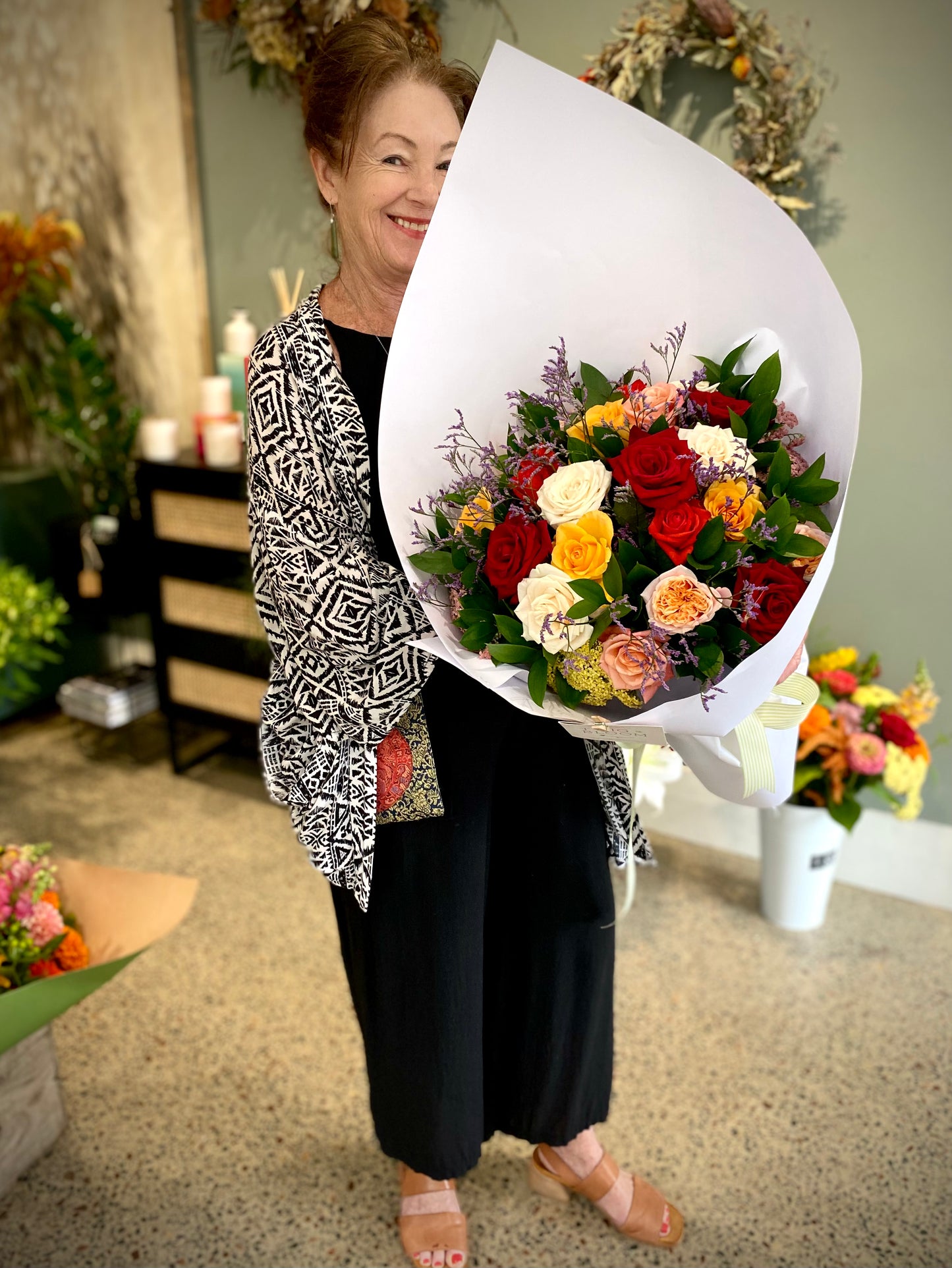 Woman holding a bunch of 24 mixed coloured roses
