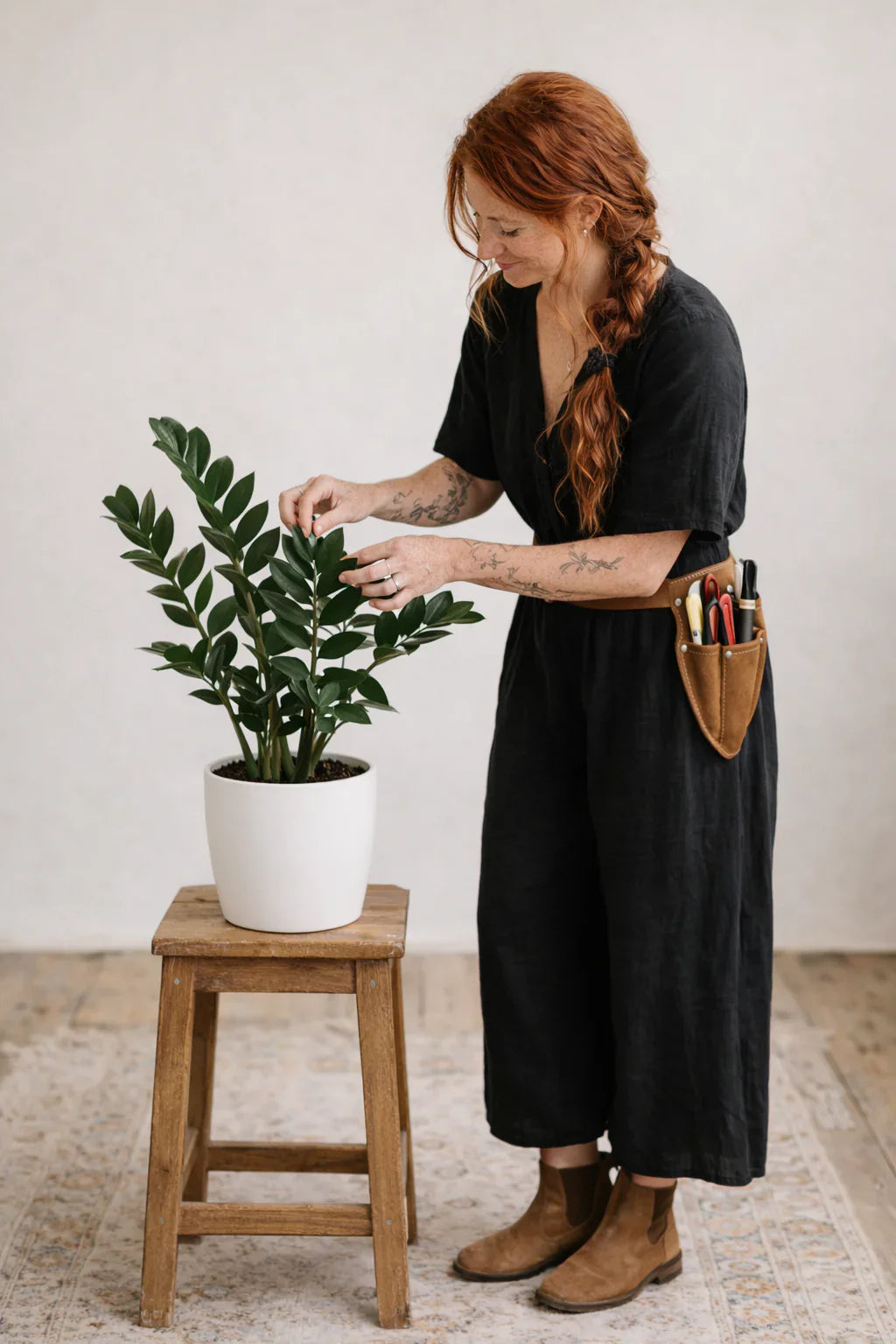 Woman tending to an indoor plant.